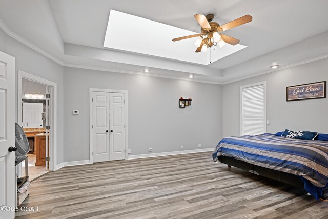 10208 Timberline Cir, Joplin, MO 64804 - bedroom featuring a tray ceiling, light wood finished floors, baseboards, a skylight, and recessed lighting