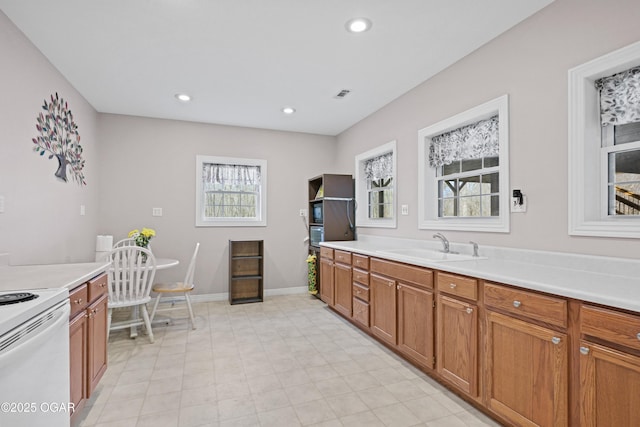 10208 Timberline Cir, Joplin, MO 64804 - kitchen with white electric range, brown cabinets, a sink, light countertops, and recessed lighting