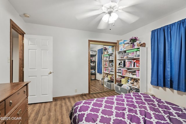 bedroom featuring wood finished floors, ceiling fan, baseboards, and a closet