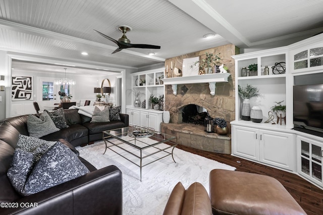 living area featuring crown molding, dark wood-type flooring, a ceiling fan, a fireplace, and a chandelier