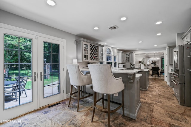 kitchen with a peninsula, glass insert cabinets, french doors, recessed lighting, and a breakfast bar