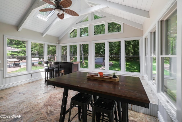 sunroom with beamed ceiling, a skylight, and high vaulted ceiling