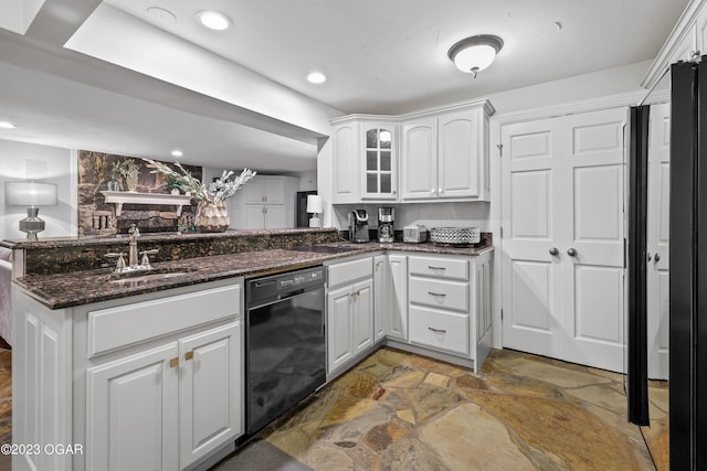 kitchen with black dishwasher, stone finish flooring, a sink, white cabinets, and glass insert cabinets