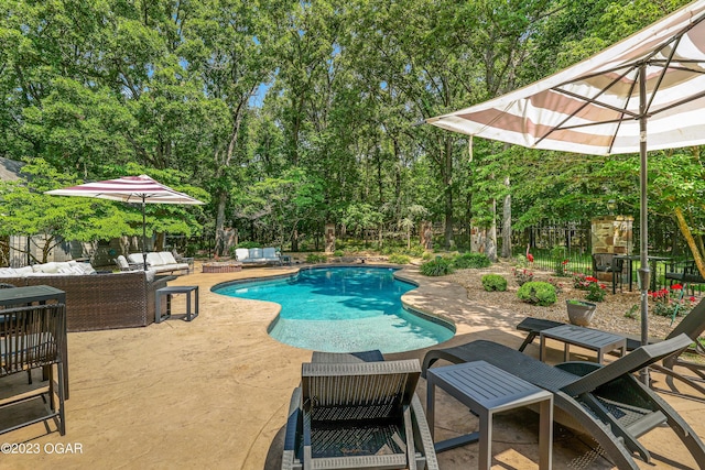 view of pool featuring a patio, fence, an outdoor living space, and view of scattered trees