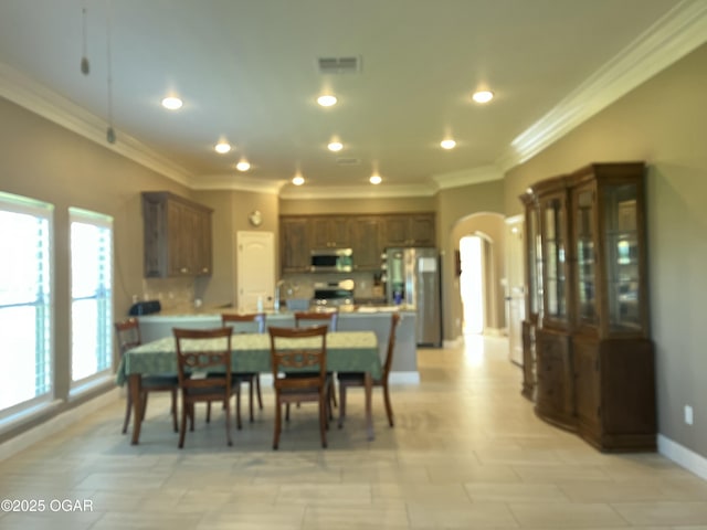 dining area with ornamental molding, arched walkways, baseboards, and recessed lighting