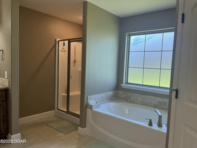 bathroom featuring a garden tub, a stall shower, vanity, and baseboards