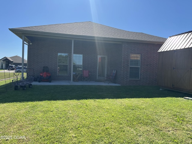 rear view of property with a patio area, brick siding, a lawn, a shed, and an outdoor structure