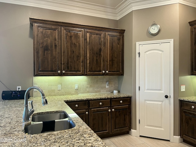 kitchen featuring a sink, decorative backsplash, dark brown cabinets, and ornamental molding