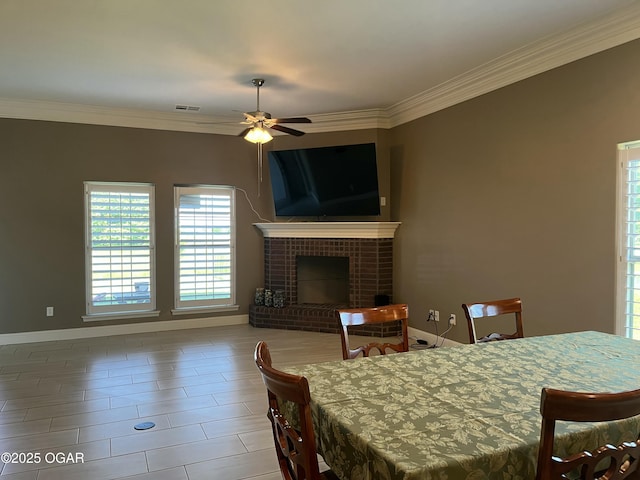 dining area with crown molding, a ceiling fan, baseboards, and a brick fireplace
