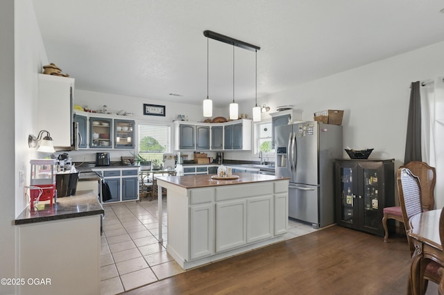 21103 Colt Ln, Diamond, MO 64840 - kitchen with appliances with stainless steel finishes, dark countertops, glass insert cabinets, decorative light fixtures, and light tile patterned floors
