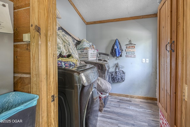 laundry room featuring wood finished floors, crown molding, baseboards, a textured ceiling, and separate washer and dryer