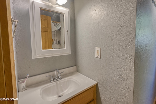 bathroom featuring a textured wall and vanity