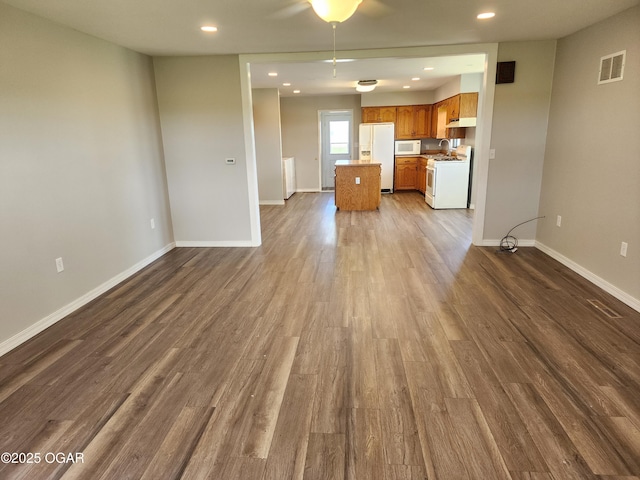 208 NW 10th Rd, Lamar, MO 64759 - unfurnished living room featuring dark wood-style flooring, baseboards, and recessed lighting