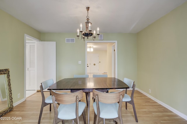 dining space with a chandelier, light wood-style flooring, and baseboards