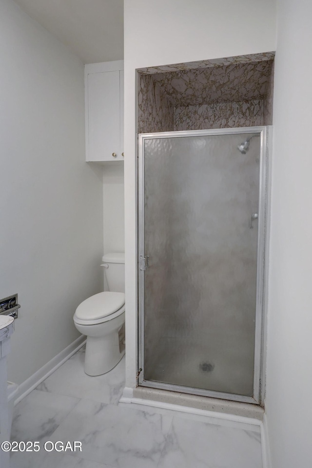 bathroom with a stall shower, toilet, marble look tile flooring, and baseboards