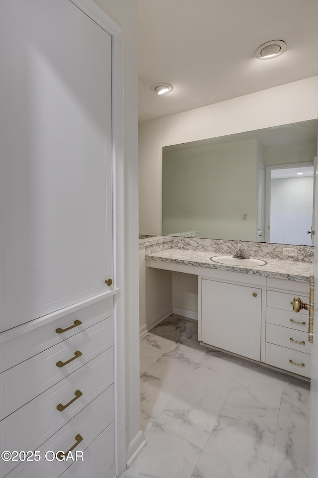bathroom featuring marble look tile flooring, vanity, and baseboards