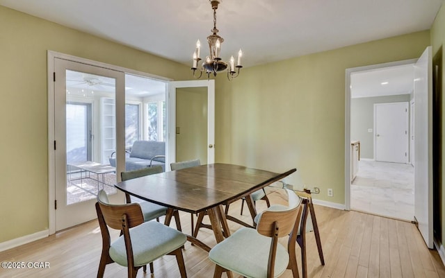 dining room featuring light wood-type flooring, a chandelier, and baseboards