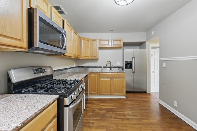 kitchen featuring stainless steel appliances, a sink, dark wood-style floors, and light stone countertops
