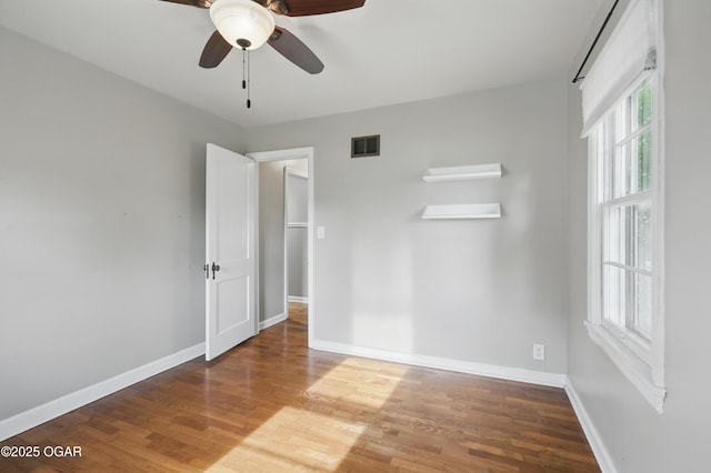 empty room featuring wood finished floors, baseboards, and ceiling fan