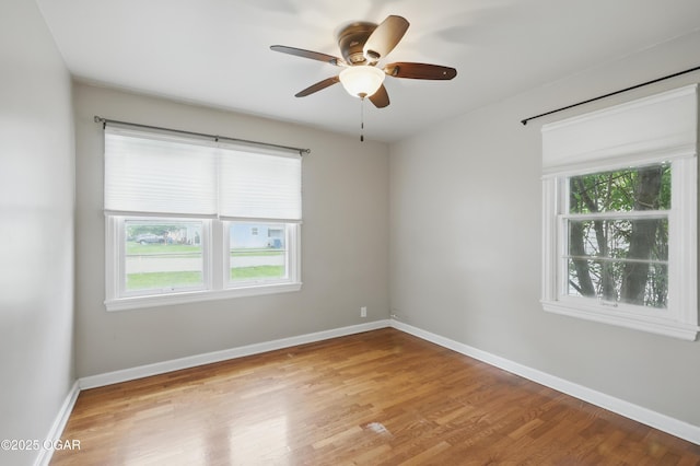 spare room with light wood-type flooring, ceiling fan, and baseboards