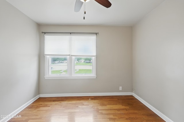 empty room with light wood finished floors, a ceiling fan, and baseboards
