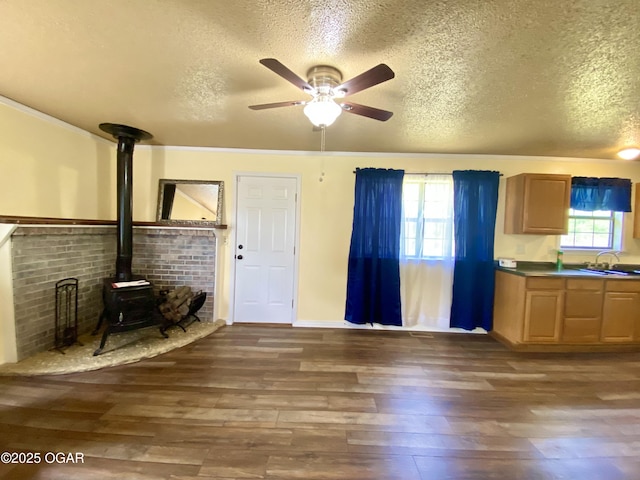 21522 Old Ritchey Rd, Granby, MO 64844 - unfurnished living room featuring a textured ceiling, a ceiling fan, a wood stove, hardwood / wood-style flooring, and a sink