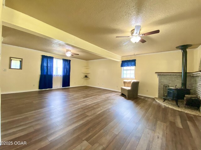 21522 Old Ritchey Rd, Granby, MO 64844 - unfurnished living room featuring a ceiling fan, a wood stove, a textured ceiling, dark wood-style flooring, and baseboards