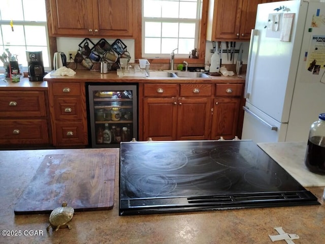6468 Dogwood Rd, Reeds, MO 64859 - kitchen featuring freestanding refrigerator, wine cooler, a sink, cooktop, and brown cabinetry