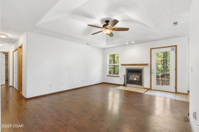 9969 Lawrence Unit 2222, Monett, MO 65708 - unfurnished living room featuring wood finished floors, ceiling fan, baseboards, a tiled fireplace, and a raised ceiling