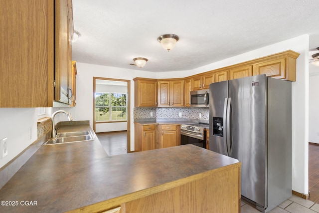 9969 Lawrence Unit 2222, Monett, MO 65708 - kitchen with appliances with stainless steel finishes, a sink, a peninsula, dark countertops, and tasteful backsplash