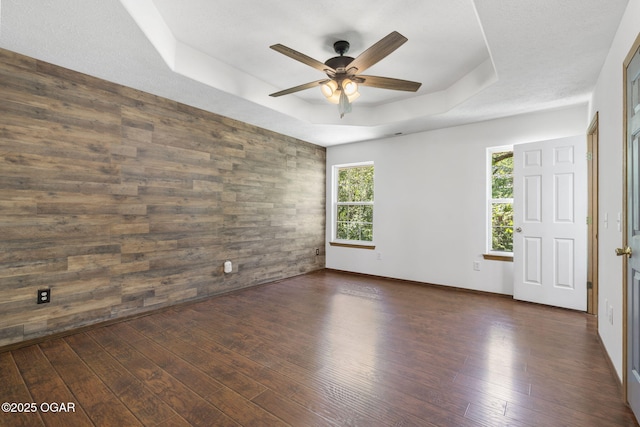 9969 Lawrence Unit 2222, Monett, MO 65708 - empty room with a raised ceiling, a ceiling fan, dark wood-style flooring, and wood walls