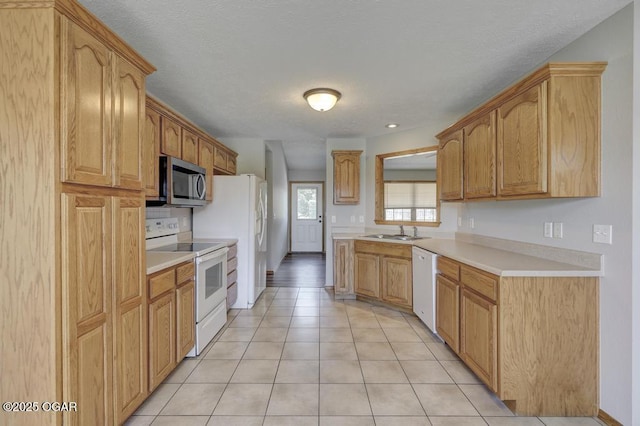 kitchen with white appliances, a sink, light countertops, light tile patterned flooring, and recessed lighting