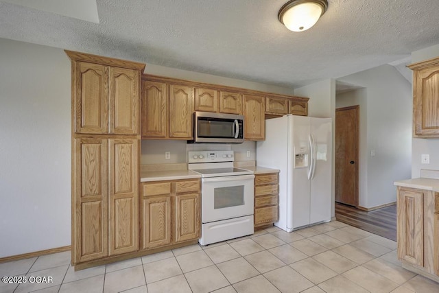 kitchen with white appliances, a textured ceiling, light countertops, light tile patterned floors, and baseboards