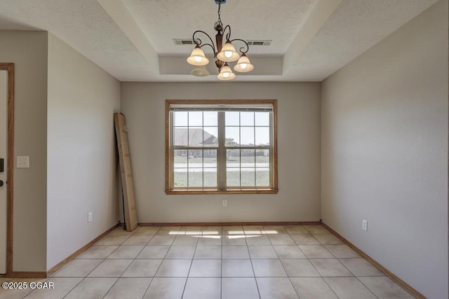 spare room with a raised ceiling, a chandelier, a textured ceiling, baseboards, and light tile patterned floors