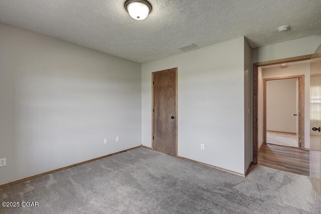 unfurnished room featuring a textured ceiling, carpet, baseboards, and a smoke detector