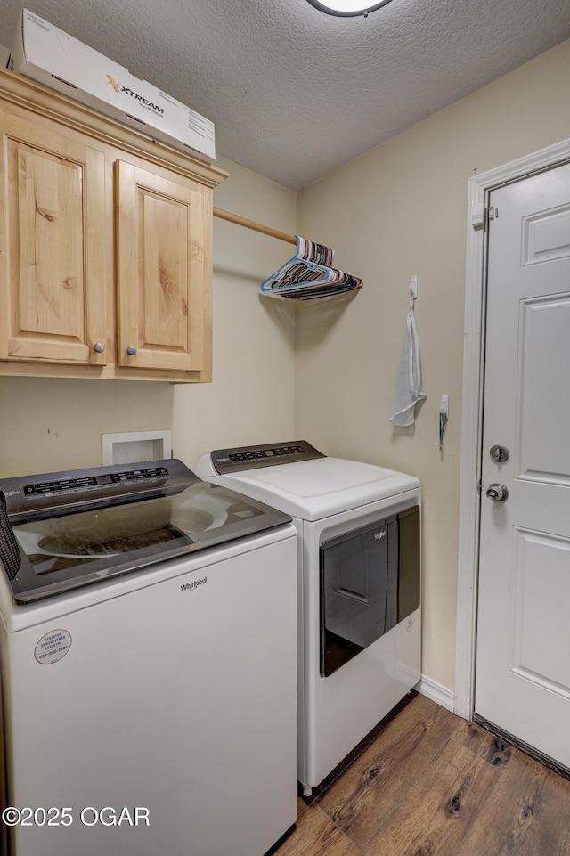 laundry area featuring washing machine and dryer, wood finished floors, cabinet space, and a textured ceiling