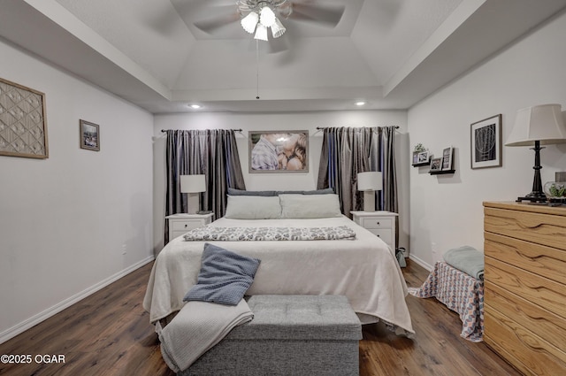 bedroom with dark wood-style flooring, vaulted ceiling, a tray ceiling, baseboards, and recessed lighting