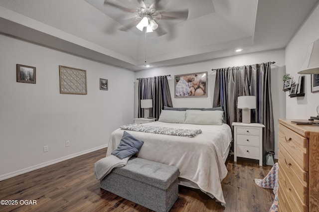 bedroom with a raised ceiling, recessed lighting, dark wood finished floors, baseboards, and a ceiling fan