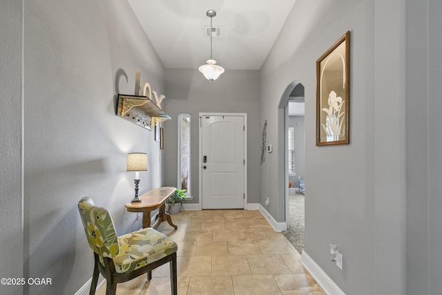 foyer entrance with arched walkways and baseboards