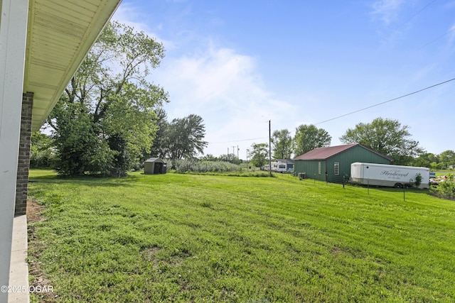 view of green lawn featuring a storage unit and an outbuilding