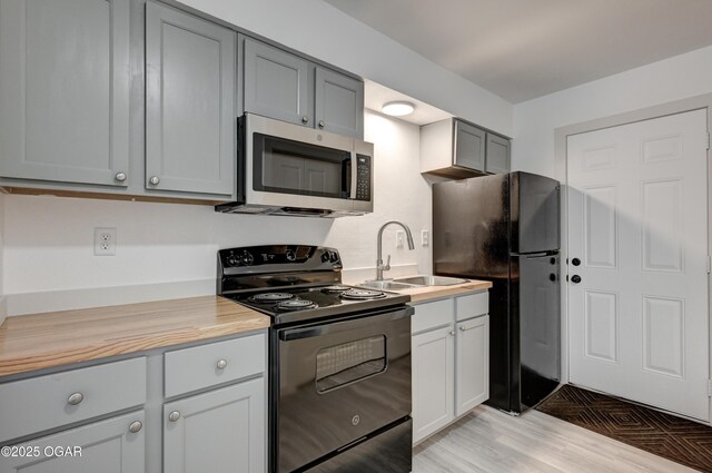 238 E 21st St, Baxter Springs, KS 66713 - kitchen featuring black appliances, a sink, light countertops, light wood-type flooring, and gray cabinets