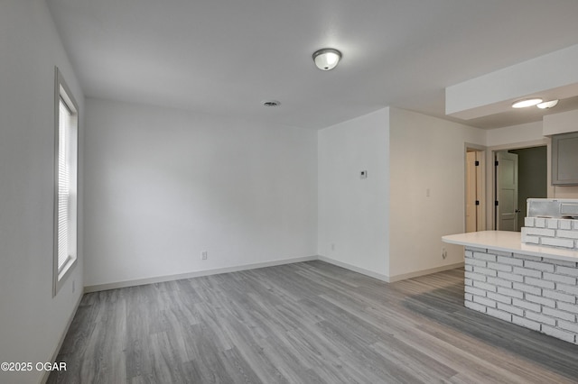 238 E 21st St, Baxter Springs, KS 66713 - unfurnished living room featuring light wood-style floors, healthy amount of natural light, and baseboards