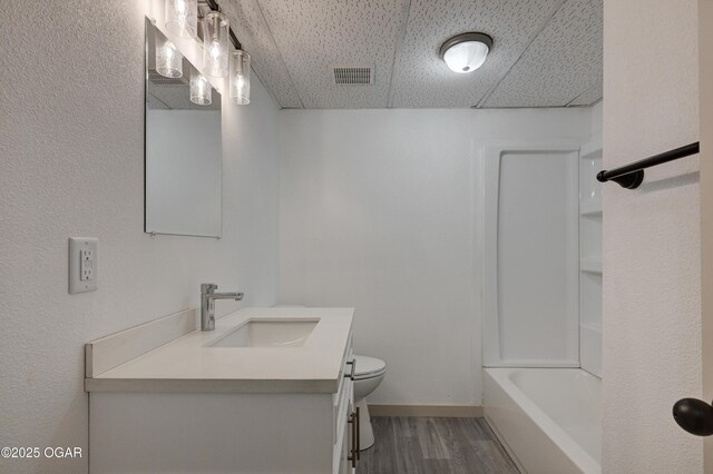238 E 21st St, Baxter Springs, KS 66713 - bathroom featuring wood finished floors, toilet, vanity, a paneled ceiling, and baseboards
