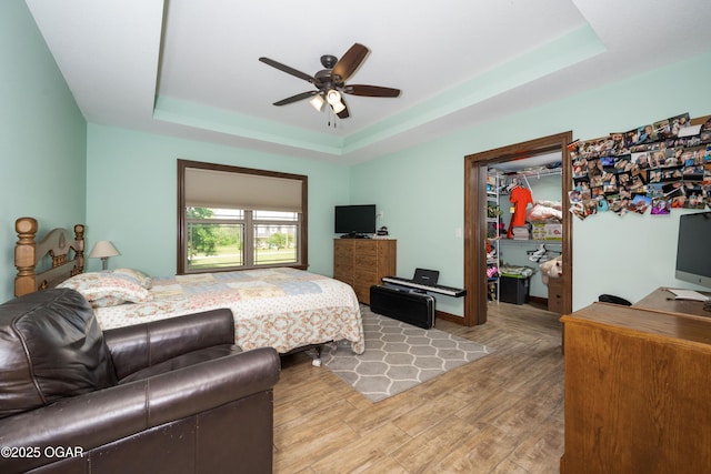 12244 County Rd 227, Oronogo, MO 64855 - bedroom with a tray ceiling, light wood finished floors, a walk in closet, a closet, and ceiling fan