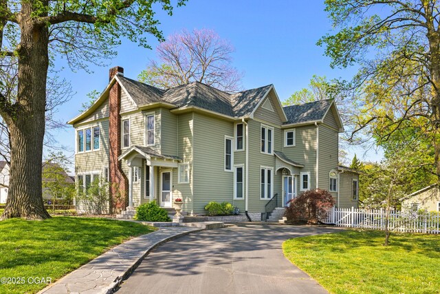 view of front facade with a chimney and asphalt driveway