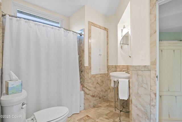 full bathroom with tile walls, toilet, a wainscoted wall, and a shower with shower curtain