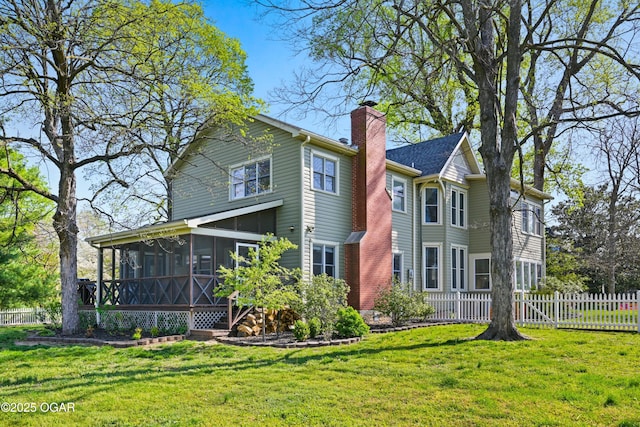rear view of house with a sunroom and a chimney