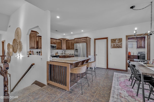 kitchen with stainless steel appliances, a breakfast bar, a peninsula, recessed lighting, and light stone countertops