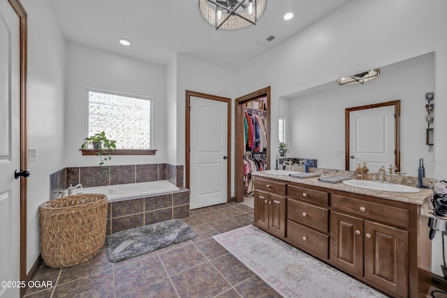 bathroom with a garden tub, double vanity, a walk in closet, tile patterned flooring, and recessed lighting