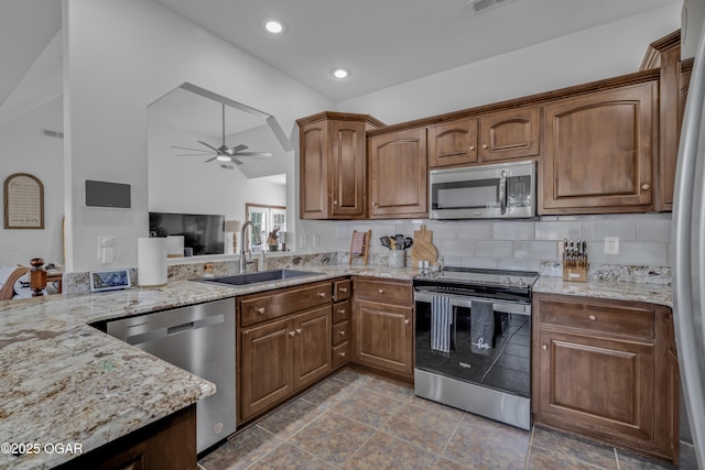 kitchen featuring appliances with stainless steel finishes, a sink, ceiling fan, light stone counters, and lofted ceiling